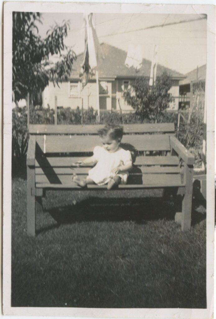 A young Margaret Monk sitting on a bench